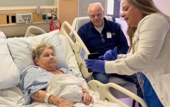 A patient in a hospital bed together with a nurse and visitor