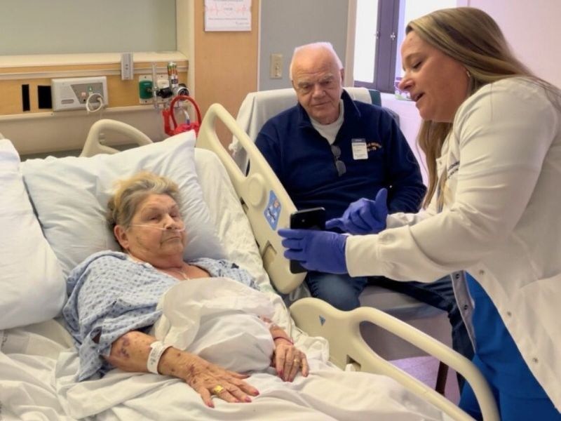 A patient in a hospital bed together with a nurse and visitor