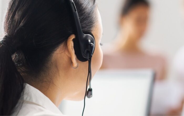 A woman wearing a headset and looking at a computer screen