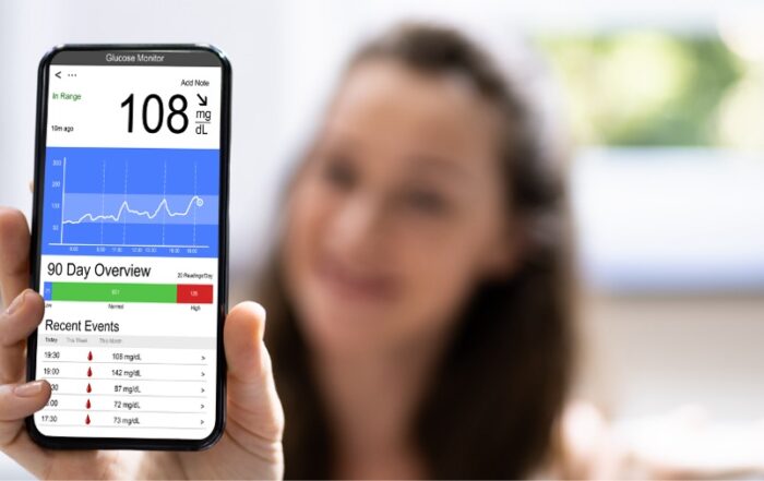 Woman holding smartphone displaying glucose monitoring app