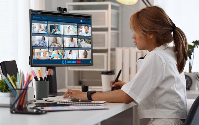 A nurse looking at a computer displaying multiple hospital patients