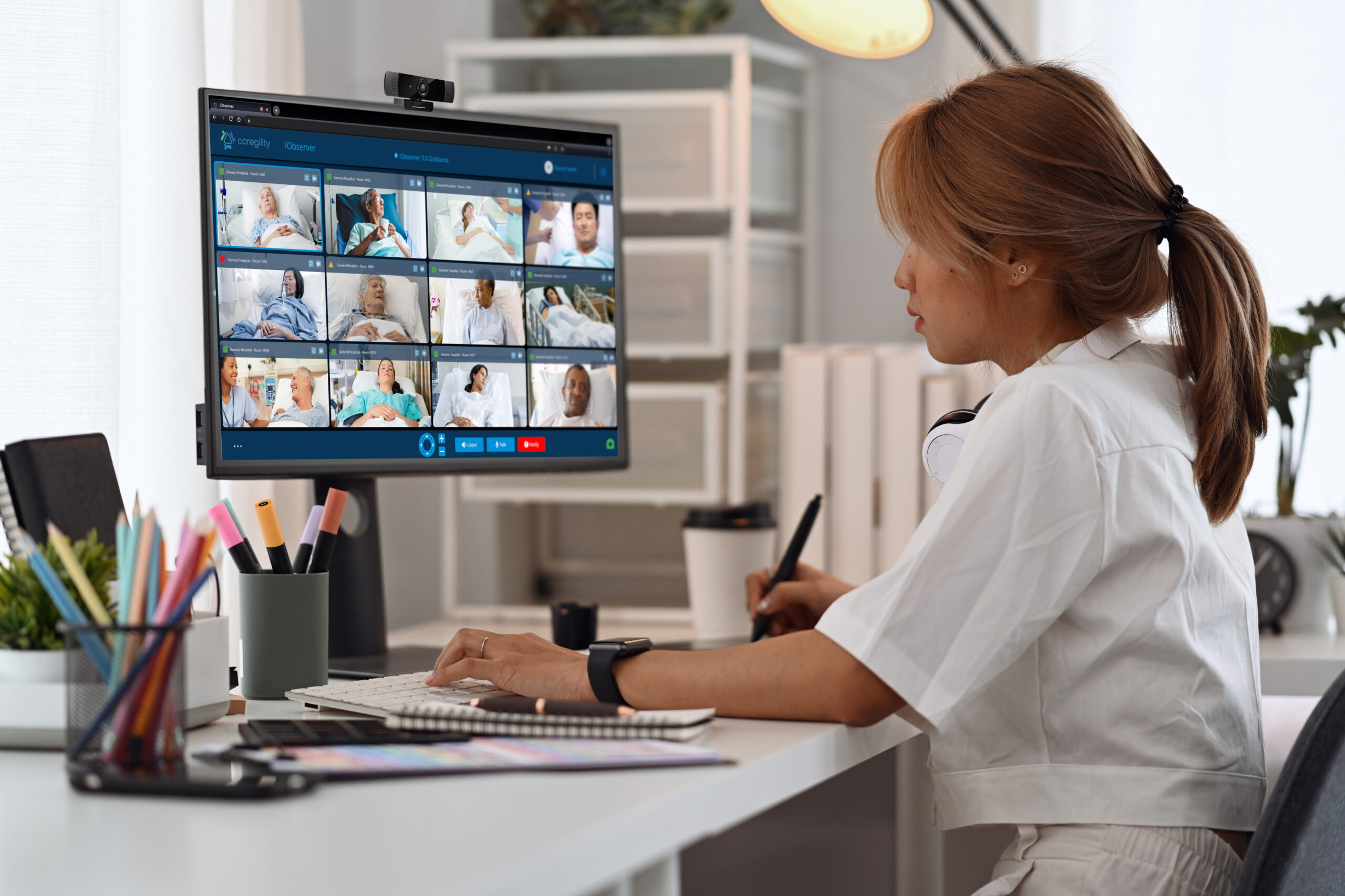 A nurse looking at a computer displaying multiple hospital patients